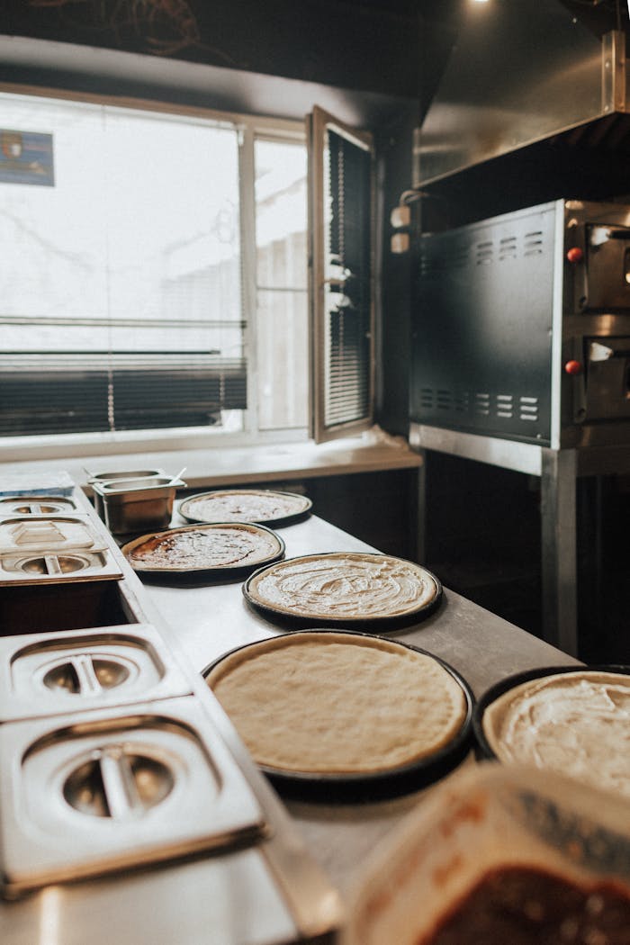 services-03 Pizza dough ready for toppings in a professional pizzeria kitchen setting.