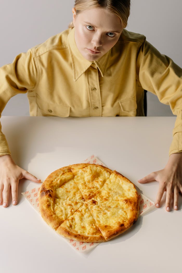 services-02 Woman in a yellow shirt gazes at a cheesecake on a table, indoors.